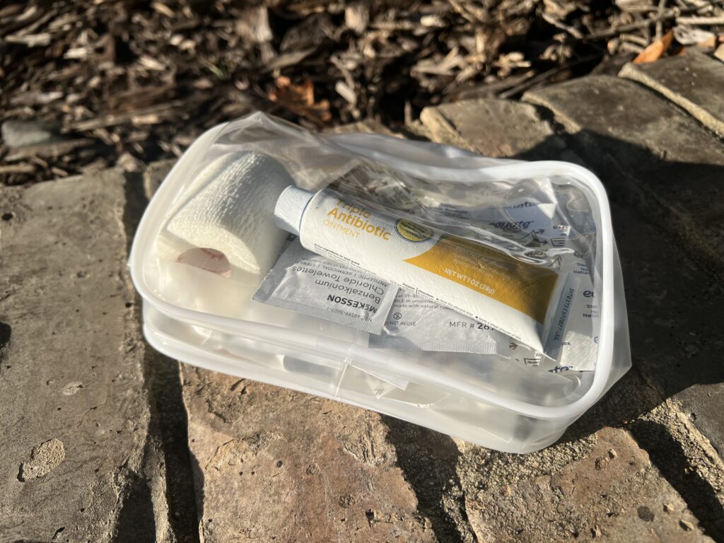 A day-hike first-aid kit packed into a clear zipper bag on a brick path