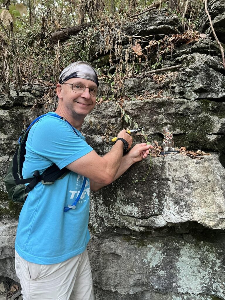 A hiker in a blue shirt wearing a headband beside a rock bluff