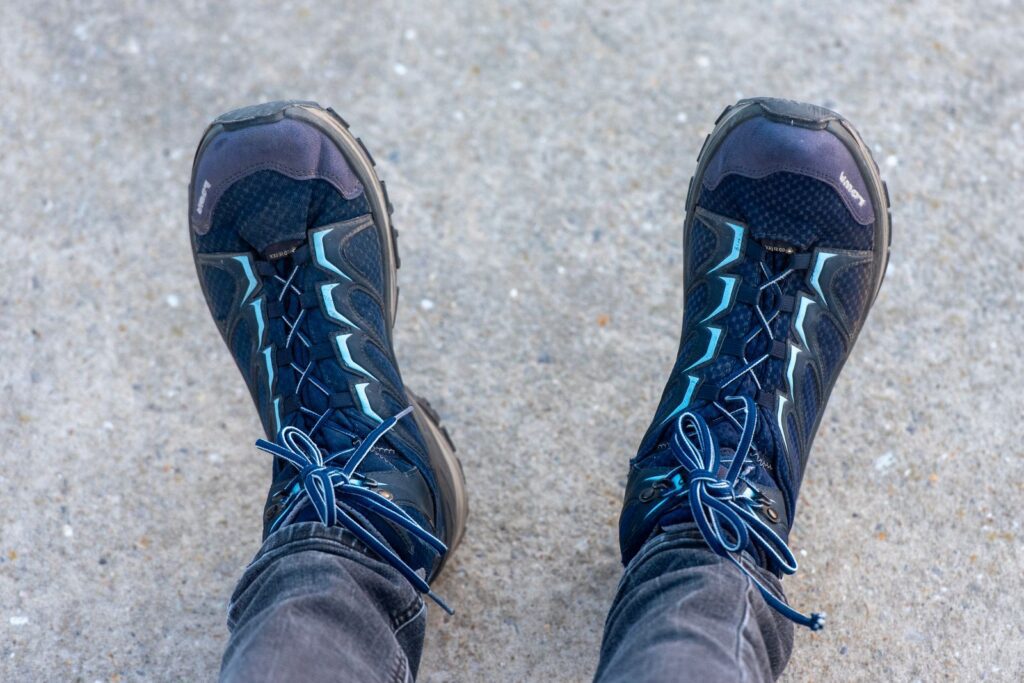 Looking straight down at a pair of blue hiking boots on pavement