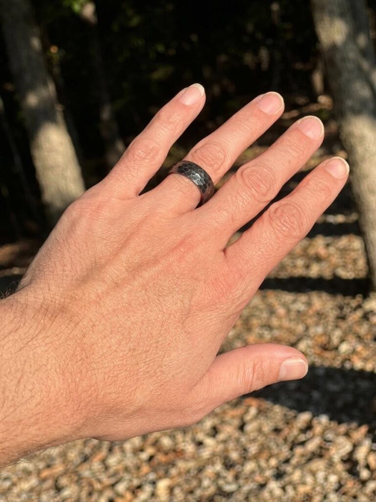 A hand wearing a ring, held over a gravel trail